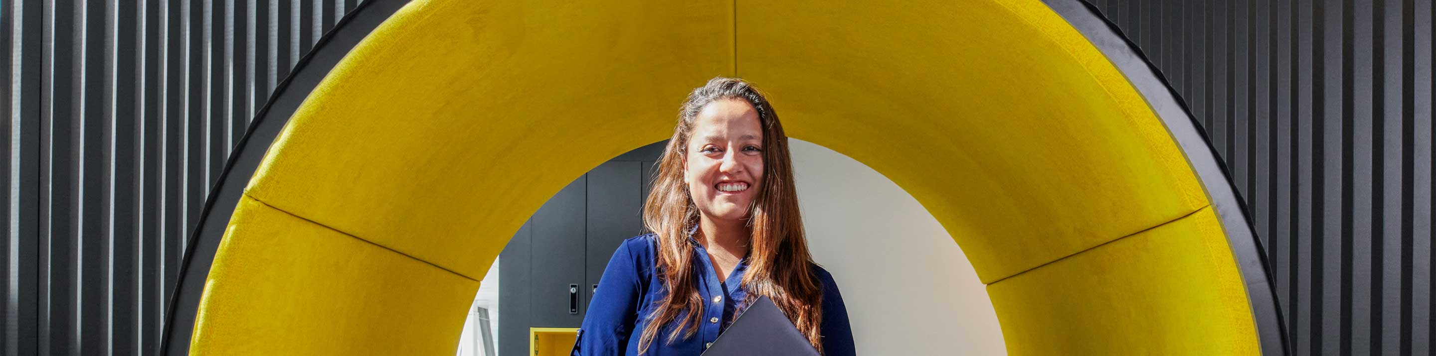 Women holding laptop in front of a big circle yellow structure
